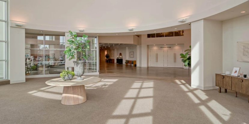 Neutral color living area with plants, wood tables, windows in atrium
